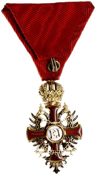 Order Franciszka Józefa, Krzyż Kawalerski, wykonany w złocie próby 18 karat (0,750), waga 12,68 grama, wersja bez dekoracji wojennych, wybity przez wiedeńskiego grawera, sygnowany na ogniwie łączącym austriackimi próbami złota i wykonawcy,V.Mayer´s Söhne in Wien” całość w oryginalnym etui firmy V.Mayer´s Söhne in Wien z data 1898. Order został ustanowiony 2 grudnia 1849 przez dziewiętnastoletniego wówczas cesarza Austrii i króla Węgier Franciszka Józefa I w pierwszą rocznicę objęcia przez niego tronu. Insygnia orderu to oznaka i gwiazda dla I i II klasy. Wąski krzyż typu kawalerskiego, emaliowany na czerwono ze złotym obramowaniem. Medalion awersu, emaliowany na biało, zawierał w środku złoty monogram założyciela “FJ”. Medalion rewersu ukazywał datę “1849”. Krzyż orderowy położony był na złotym dwugłowym, podwójnie ukoronowanym, częściowo emaliowanym na czarno orle monarchii habsburskiej, noszącym w dziobach złoty łańcuch, na dolnej części którego widniała dewiza panowania Franciszka Józefa, “Viribus unitis” (“Zjednoczonymi siłami”). Katalog odznaczeń austriackich. A. Marko pozycja nr 098c.