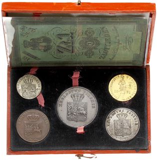 pamiątkowe pudełko z monetami i banknotem Powstania Listopadowego oklejone ozdobnym papierem koloru czerwonego z wytłoczonym złotym napisem PAMIATKA / 1831 i ozdobną ramką wokół krawędzi pudełka. We wnętrzu pudełka w zagłębieniach monety. Stan zachowania: dukat (II-), 5 złotych (II-), 2 złote (III), 10 groszy (II-), 3 grosze (III), i banknot (V), stan pudełka - bardzo dobry, egzemplarz z aukcji WCN 45/399
