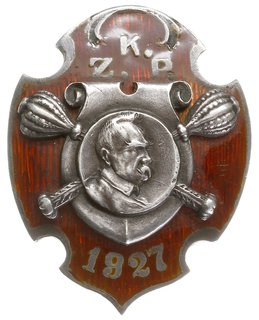 odznaka pamiątkowa KZP 1927, dwuczęściowa w kształcie tarczy herbowej pokrytej czerwoną emalią, pośrodku srebrna tarcza polska”z dwoma buławami marszałkowskimi i medalionem, na którym umieszczone jest popiersie marszałka Józefa Piłsudskiego, powyżej srebrne litery K Z P, poniżej data 1927. Na stronie odwrotnej numer 107 i dwa druty mocujące tarczę. Nakrętka niesygnowana, tombak srebrzony 40 x 32 mm. Nieznana jest przynaleźność tej odznaki. Można jednak przypuszczać, że została wykonana dla uczestników corocznych marszów szlakiem I Kompanii Kadrowej z metą w Kielcach.